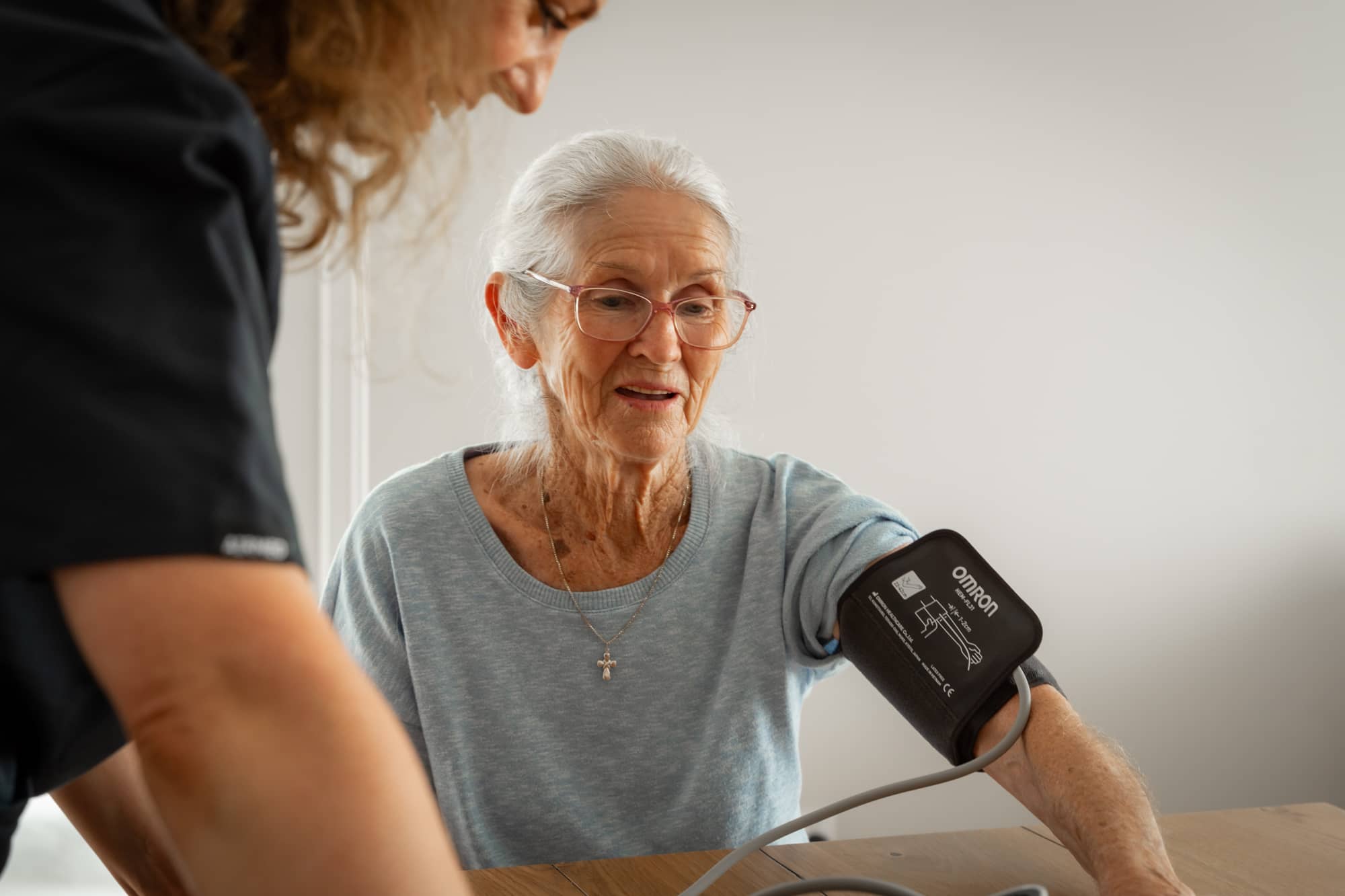 Aged care placement services allowing old woman to have blood pressure checked