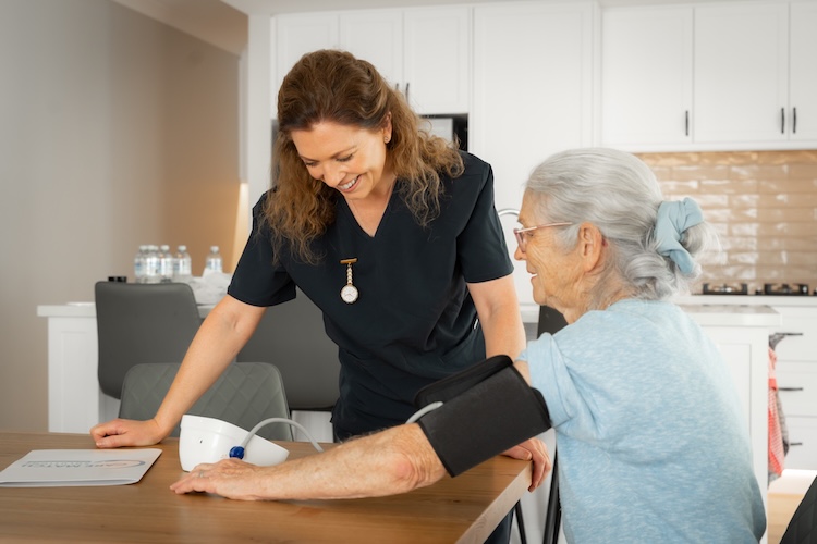 lady helping older lady check blood pressure for home care