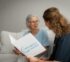assistant reading age care brochure to old lady