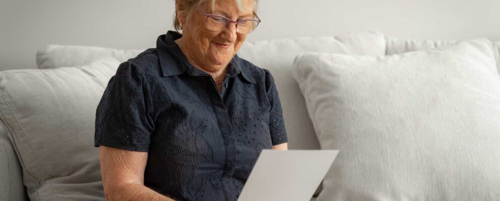 higher-everyday-living-fee-aged-care Elderly woman in her lounge room reading piece of paper explaining higher everyday living fee for aged care