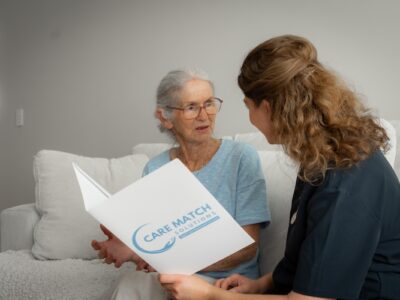 assistant reading age care brochure to old lady