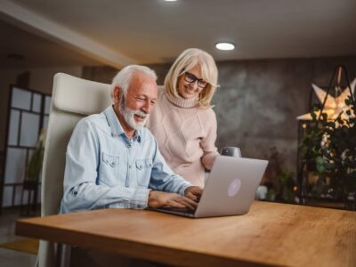 Elderly couple on laptop looking up how to get into aged care facility